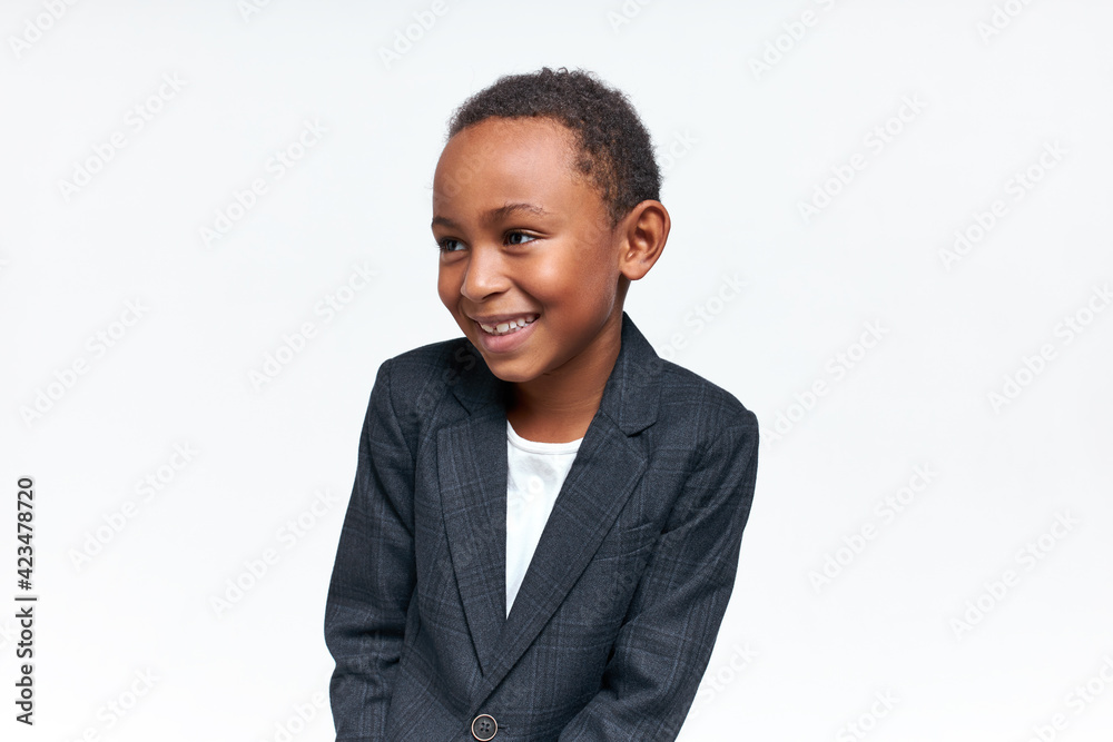 Portrait of charming stylish Afro American child with short curly hair and adorable happy smile, laughing, having nice time posing against blank white background with copy space for your text Portrait of charming stylish Afro American child with short curly hair and adorable happy smile, laughing, having nice time posing against blank white background with copy space for your text