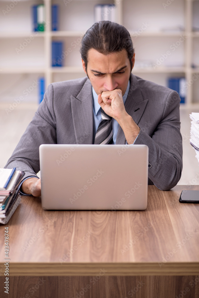 Young male employee unhappy with excessive work in the office Young male employee unhappy with excessive work in the office