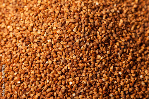 Background heap bunch of buckwheat close up. Macro photo food buckwheat groats. Texture background grain buckwheats groats. Image food product for porridge cooking. Copy space