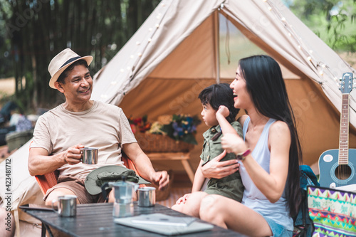 Summer camping in the mountains, spruce forest on background..Back view group of tourists having a rest together around campfire, enjoying fresh air near tent.happy family on vacation.