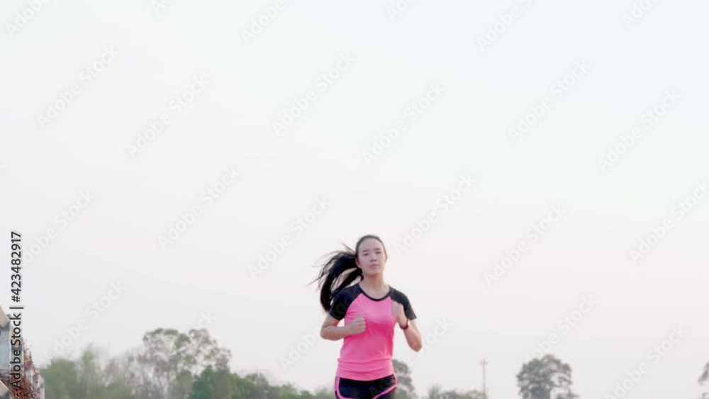 Young sport Asian woman running exercise on dam outdoor on natural light at evening on country forest background. Slim Chinese female runner workout jog training for good health in pink sportswear Young sport Asian woman running exercise on dam outdoor on natural light at evening on country forest background. Slim Chinese female runner workout jog training for good health in pink sportswear