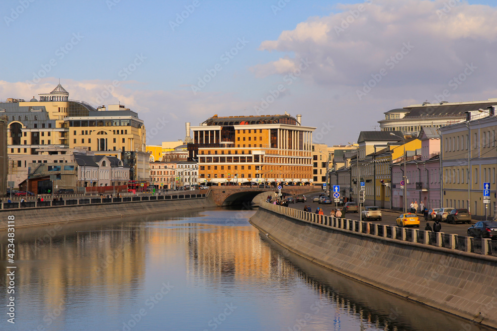 City landscape with the Kadashevskaya embankment, Balchug street and Maly Moskvoretsky bridge, as well as their reflections in the canal. 