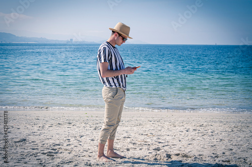 man walking on the beach using mobile phone photo