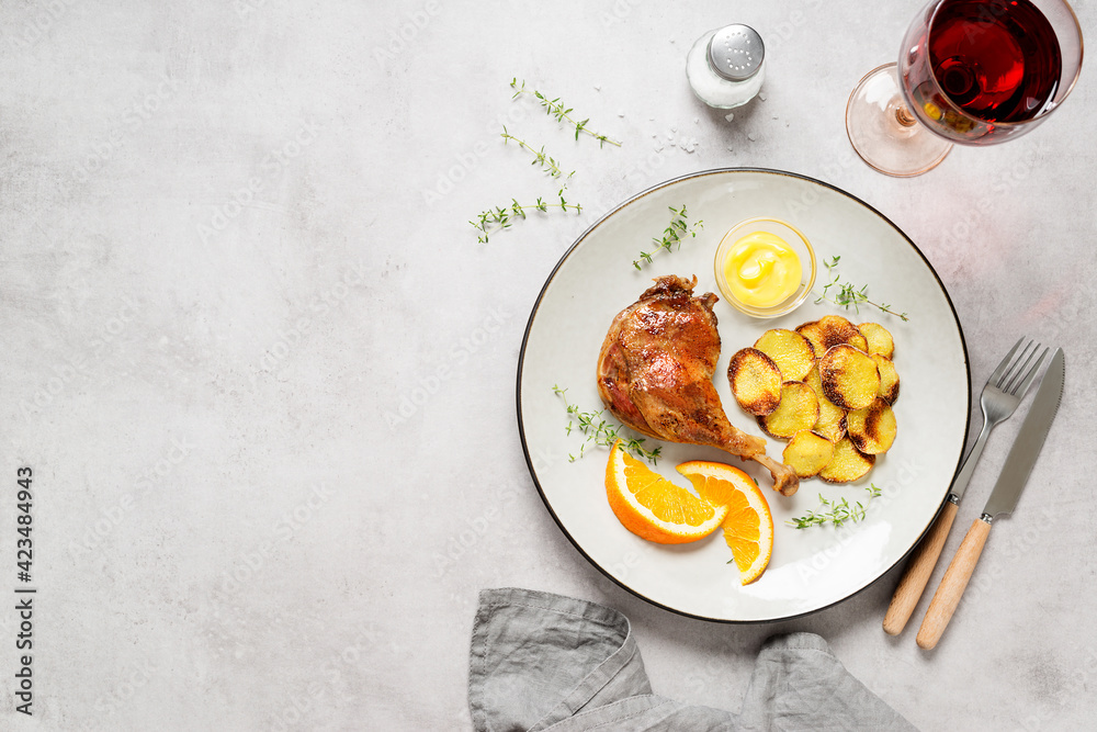 Duck leg confit served with potato chips and mustard sauce .Traditional french cuisine. Light gray background, top view. Space for text