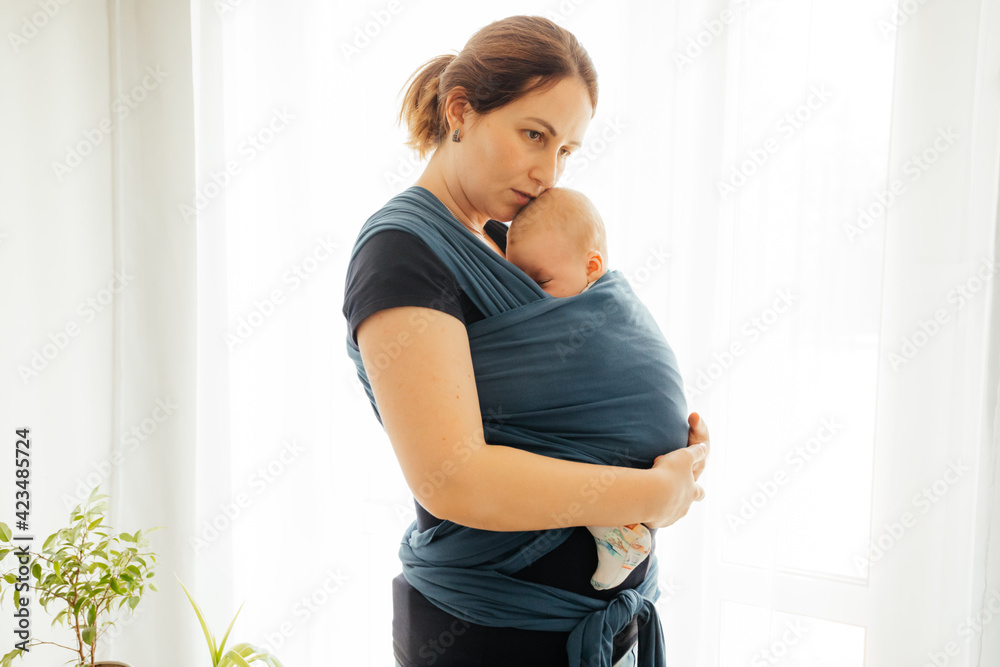 Carrying newborn in baby wrap to comfort him