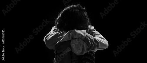 Little daughter sitting while holding her legs in sad emotion