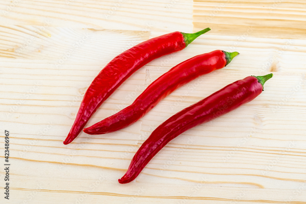 three hot red chili peppers on a light beige background