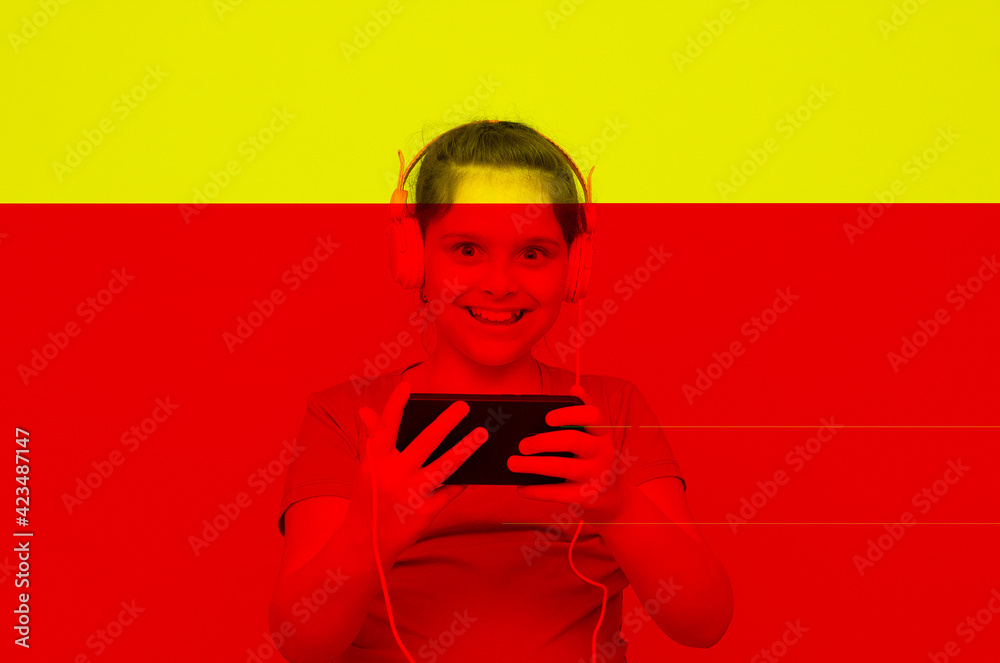 Gamer Kid. 10 years old child holding a phone video game playing a video game in a computer graphic light composition ambient. Studio shot. Gaming addiction concept yellow and red overlay Gamer Kid. 10 years old child holding a phone video game playing a video game in a computer graphic light composition ambient. Studio shot. Gaming addiction concept yellow and red overlay
