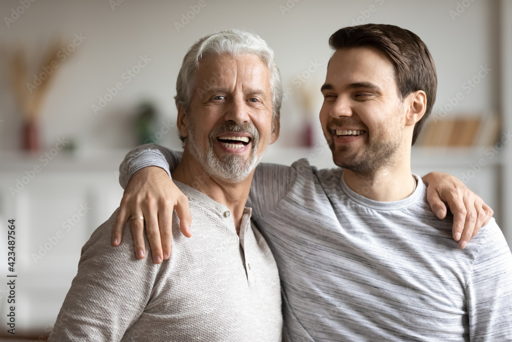 Portrait of happy middle-aged Caucasian father hug adult grownup 30s son, feel proud thankful. Smiling millennial 20s man embrace mature optimistic grey-haired dad parent. Family unity concept. Portrait of happy middle-aged Caucasian father hug adult grownup 30s son, feel proud thankful. Smiling millennial 20s man embrace mature optimistic grey-haired dad parent. Family unity concept.