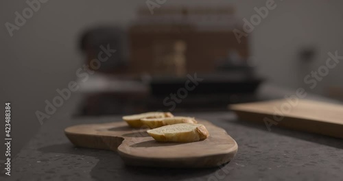 Man put baguetteslices on olive wood board photo