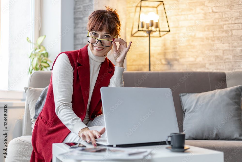 happy older woman with glasses working on laptop at home happy older woman with glasses working on laptop at home