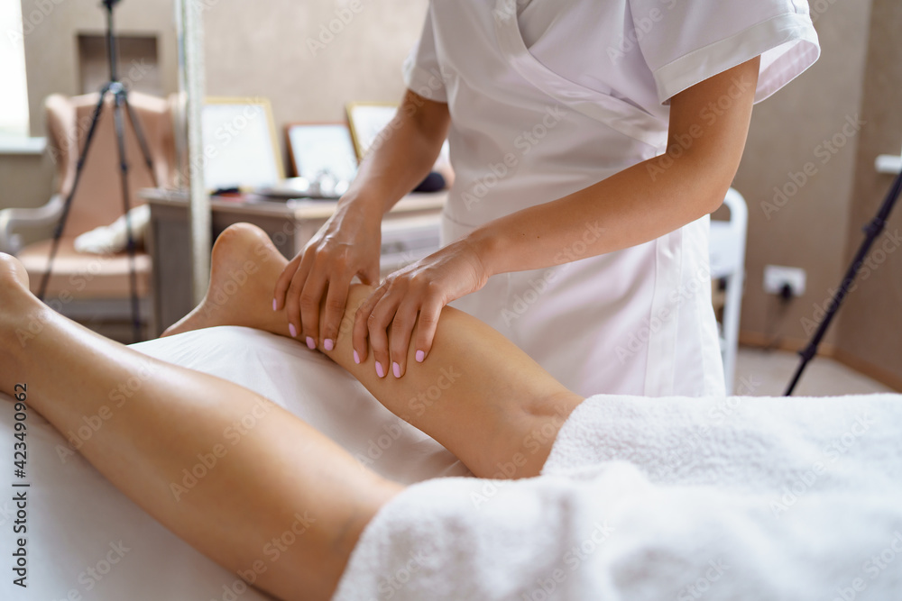 Fototapeta premium Professional massage therapist massages the soles, legs of adult woman lying on massage table, close-up. Lady gets relaxing massage. Concept of body care.
