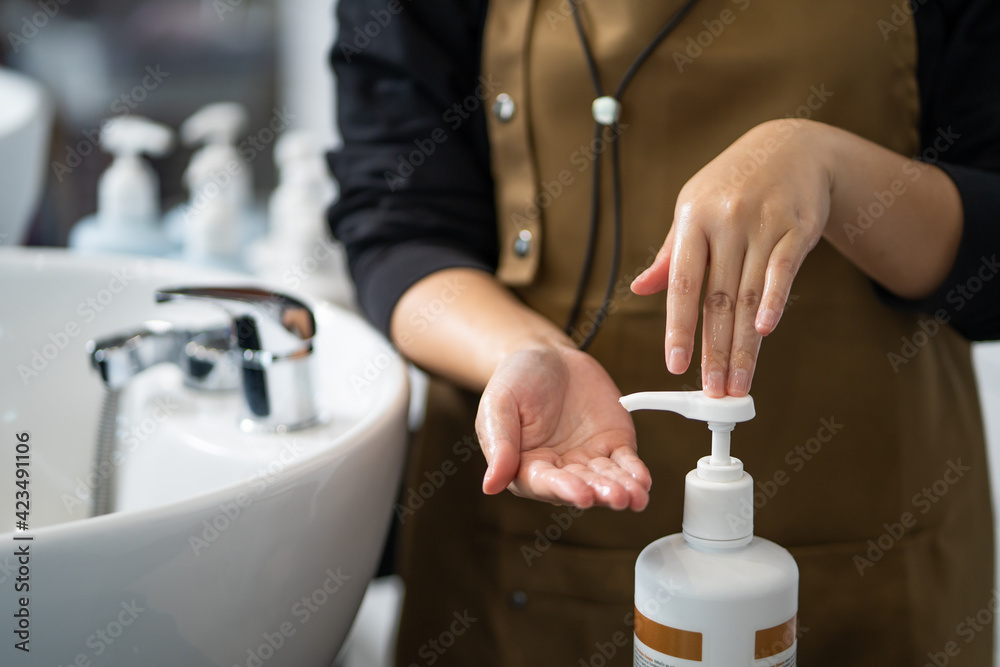 Hand of women hairdresser press on the bottle of shampoo or conditioner  before use it to wash customer inside of hair salon studio. Beauty and  fashion product and service concept. Photos