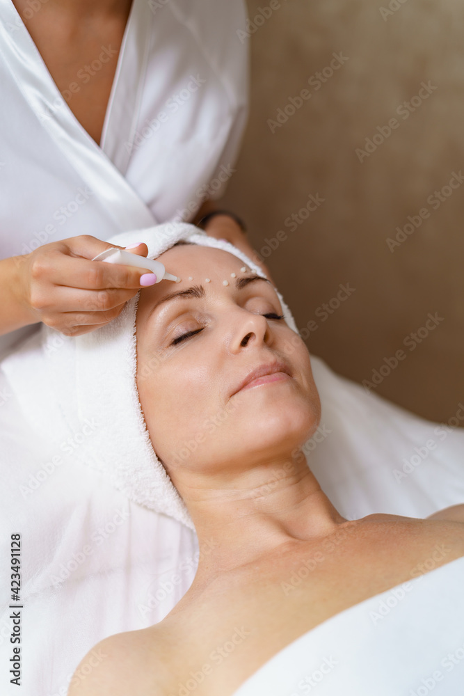 Face and Eye cream treatment or therapy. Dermatologist applying lotion on female skin