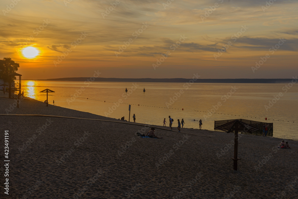 sunset over a river beach with vacationers