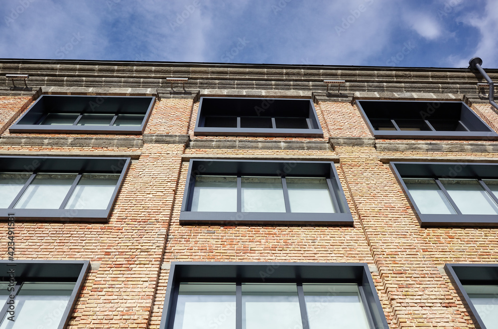 Fototapeta premium Brick building with windows and downspout against blue sky