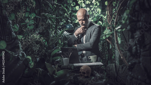 Businessman working in the jungle and thinking