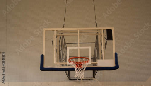 Red basketball hoop with white mesh and transparent shield in the gym