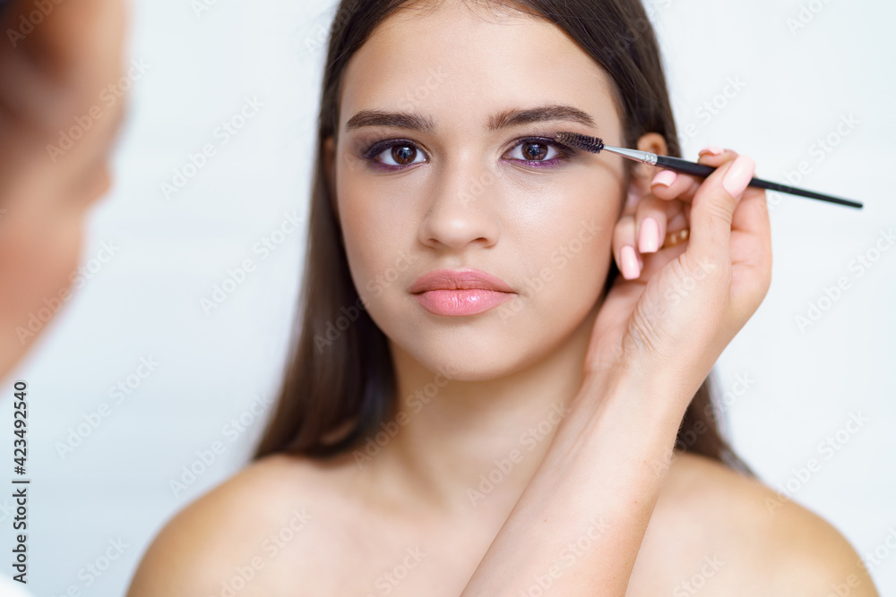 Professional makeup artist working with client in dressing room on white background Professional makeup artist working with client in dressing room on white background