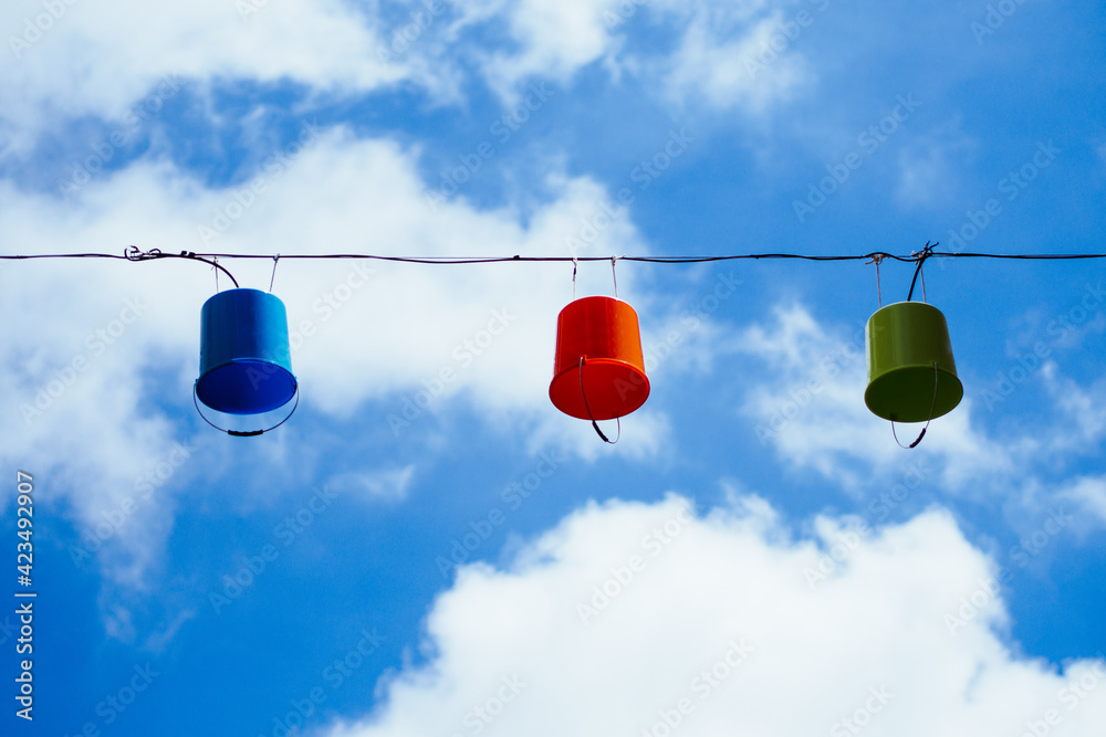 three hanging buckets with light on cable in front of blue sky three hanging buckets with light on cable in front of blue sky