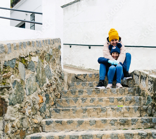 mother and daughter looking at the camera happily sitting on the stairs