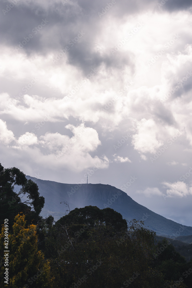 stormy moody sky with sunrays peaking through on top of the mountains in Tasmania, Australia stormy moody sky with sunrays peaking through on top of the mountains in Tasmania, Australia