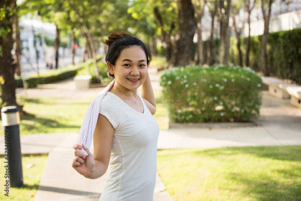Asian woman hold towel after running in park