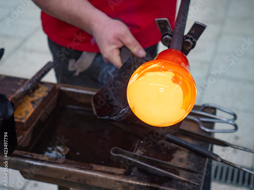 Glass blower forming beautiful piece of glass by traditional hand method.