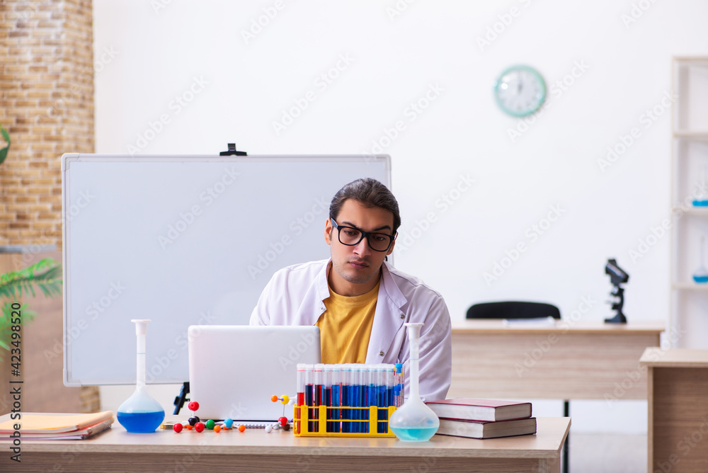 Young male chemist teacher in front of white board Young male chemist teacher in front of white board