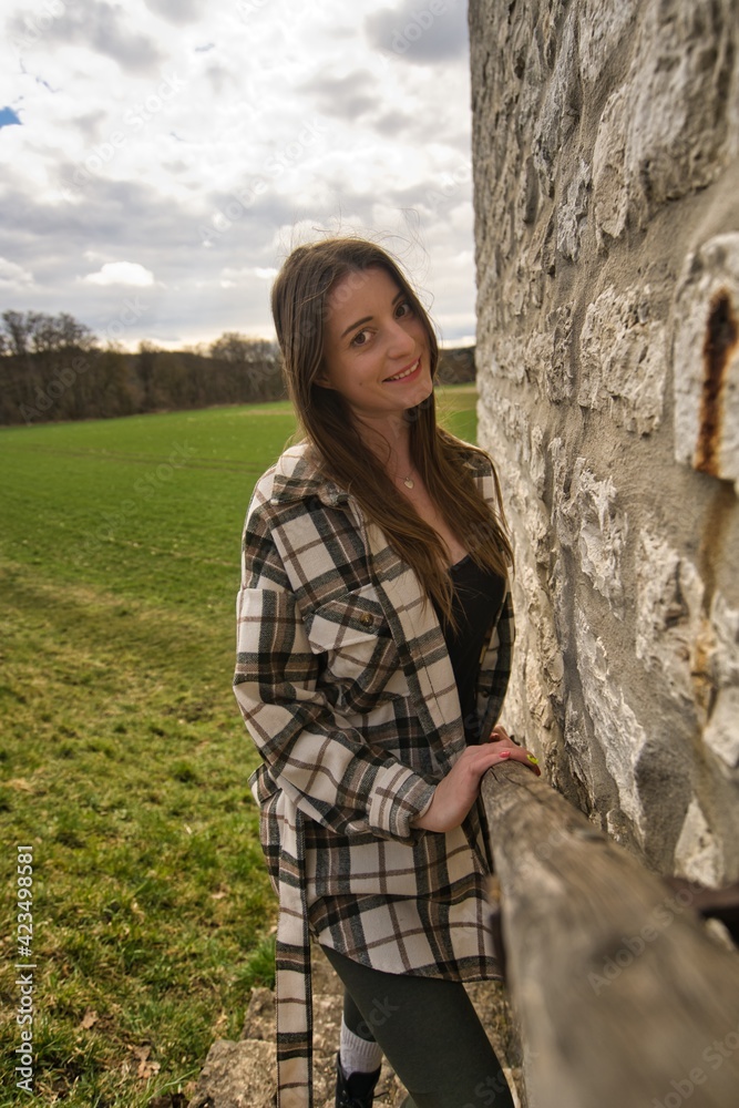 Fotografie von einer jungen frau lehnend an einer Mauer aus Ziegelsteinen und einer grünen Wiese im Hintergrund. Fotografie von einer jungen frau lehnend an einer Mauer aus Ziegelsteinen und einer grünen Wiese im Hintergrund.