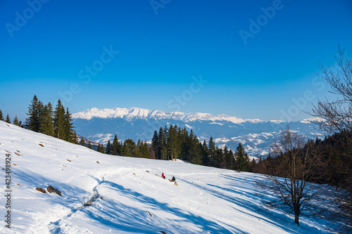 Obraz na płótnie Hikers resting on snowy alpine meadow with view over Bucegi mountain range in Romanian Carpathians w salonie