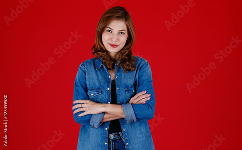 Portrait studio shot of 45s Asian woman wearing jeand clothes and pose to camera with smile face and self-confidence on red background photo