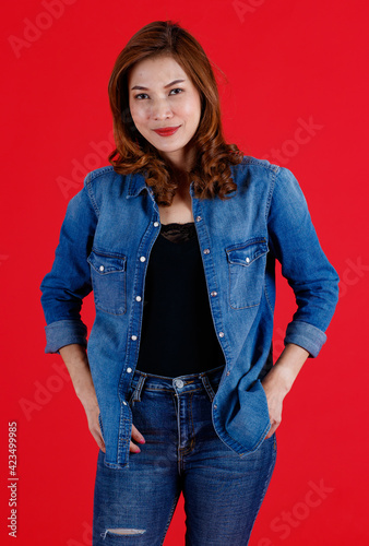 Portrait studio shot of 45s Asian woman wearing jeand clothes and pose to camera with smile face and self-confidence on red background photo