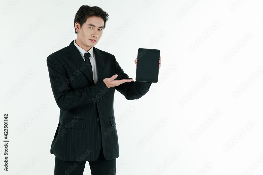 Portrait of self-confidence young and handsome Asian businessman in black suit standing in elegant pose holding and present tablet computer, copy space studio shot isolated on white background Portrait of self-confidence young and handsome Asian businessman in black suit standing in elegant pose holding and present tablet computer, copy space studio shot isolated on white background