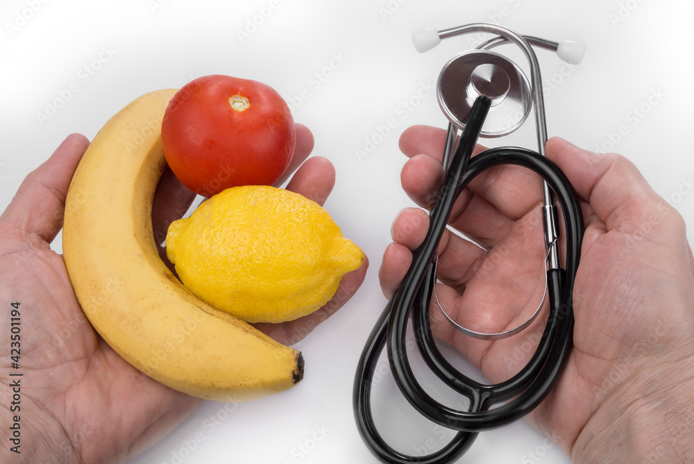 Healthy lifestyle and fruit versus stethoscope in the hands Healthy lifestyle and fruit versus stethoscope in the hands
