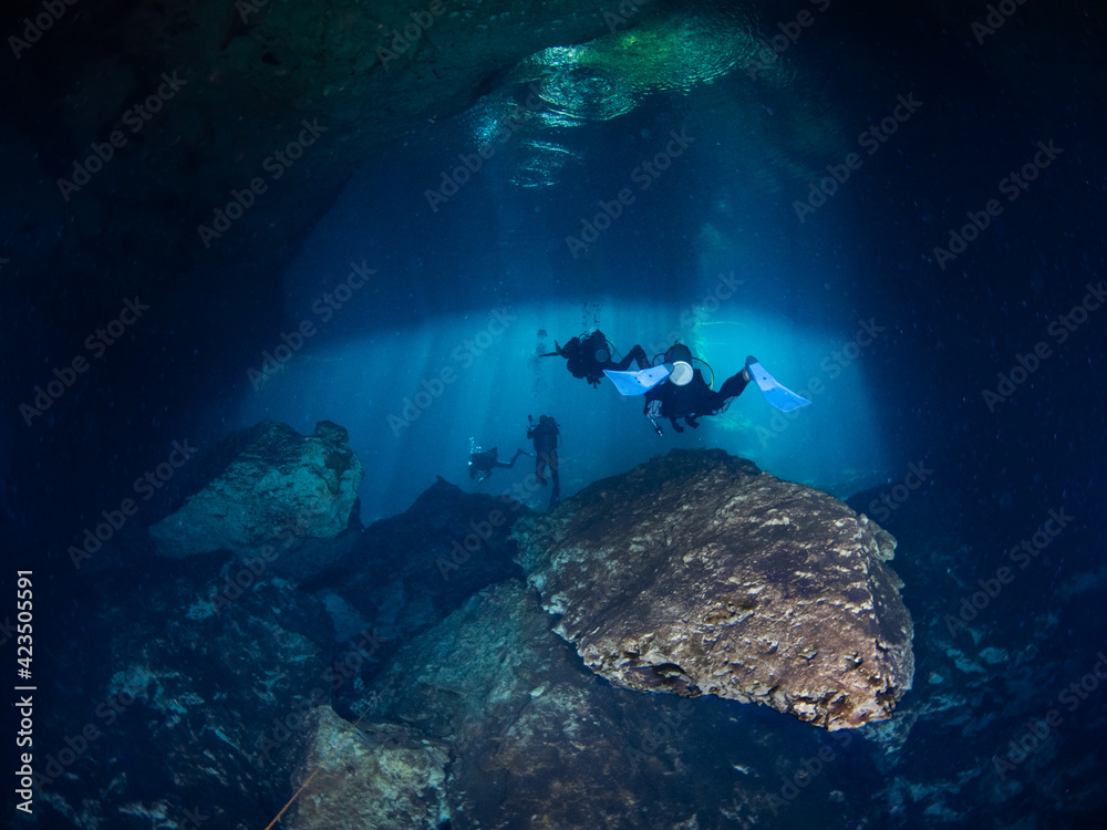 Scuba diving under sunbeams into a cenote (Cenote Ponderosa, Playa del Carmen, Quintana Roo