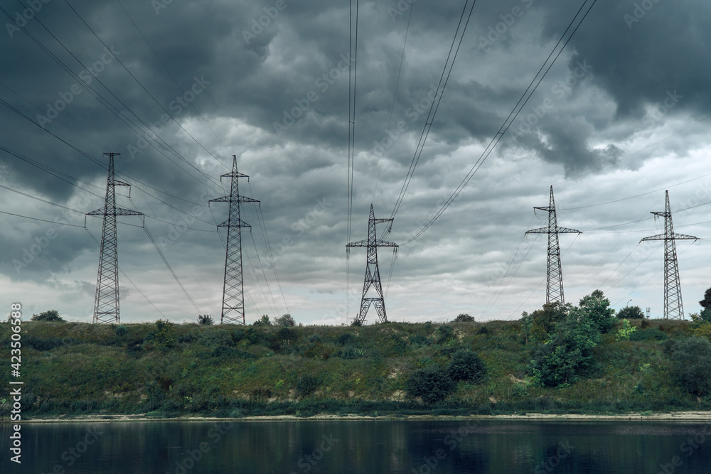 five high voltage towers with electrical wires on dark cloudy sky background
