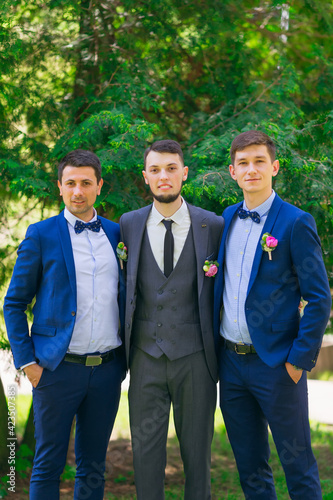 Cheerful, young, energetic witnesses in blue suits with boutonnieres next to the groom.