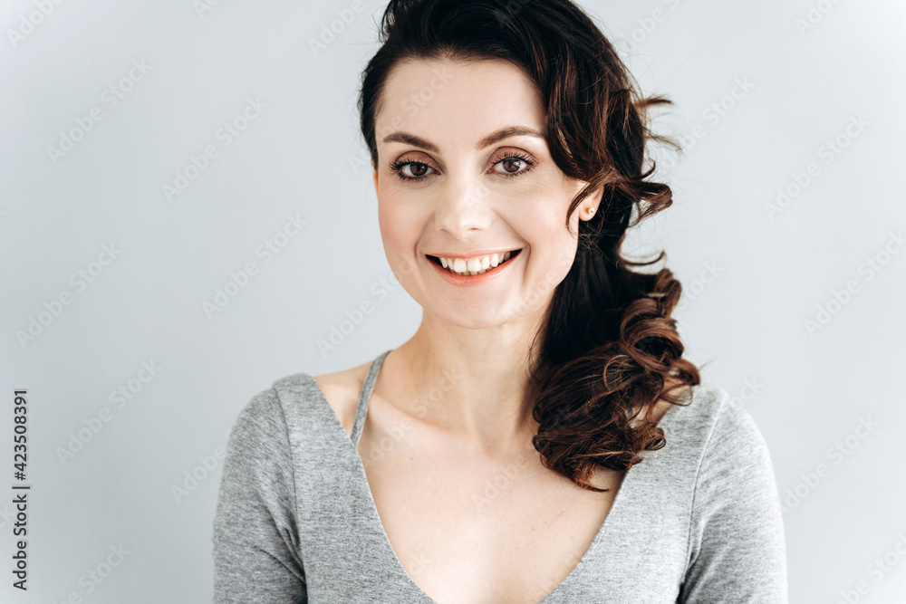 Beautiful, young woman smiling, looking at the camera. Girl posing isolated on a gray wall.
