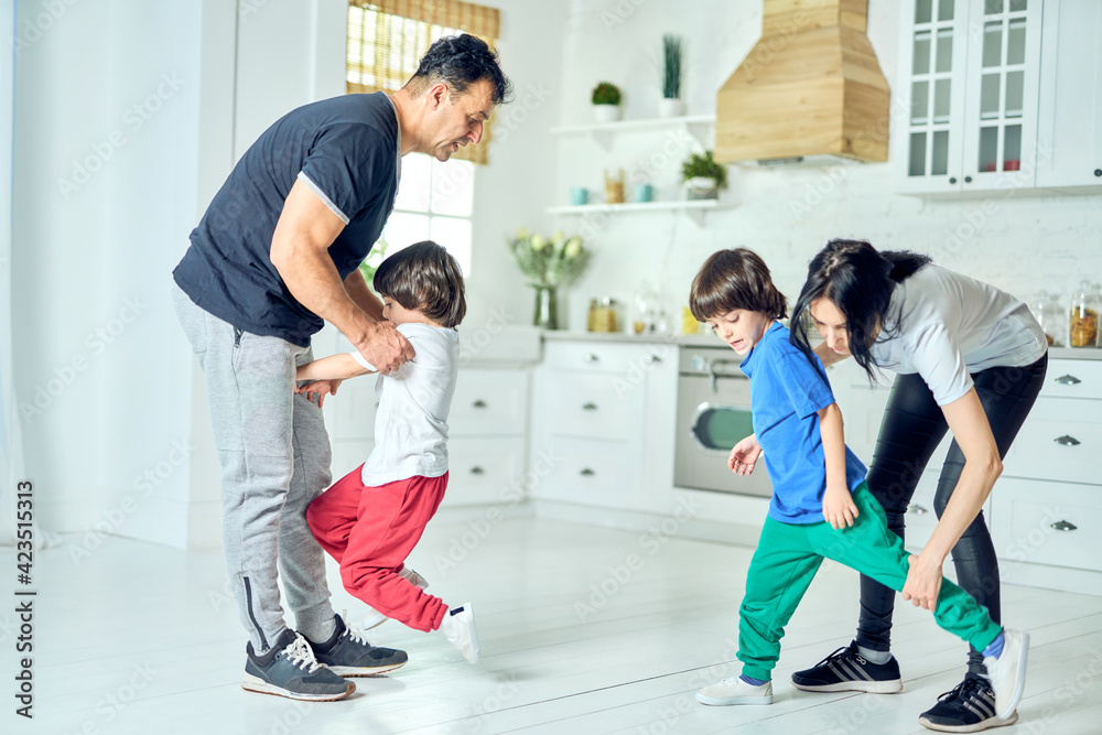 Active middle aged latin parents making two little boys do exercises in the morning at home. Healthy lifestyle Active middle aged latin parents making two little boys do exercises in the morning at home. Healthy lifestyle
