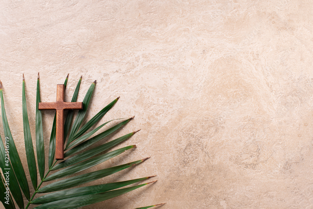 Palm Sunday concept. Wooden cross over palm leaves. Reminder of Jesus