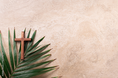 Palm Sunday concept. Wooden cross over palm leaves. Reminder of Jesus sacrifice and Christ resurrection. Easter passover. Eucharist concept. Christianity symbol and faith © jchizhe