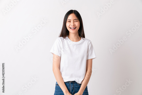 Studio shot of cheerful beautiful Asian woman in white t-shirt and stand smiling with braces on white background.