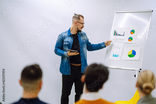 Male business coach speaker giving flipchart presentation  speaker leading consulting training convincing client group employees  mentor leader explain strategy schedule at team meeting.