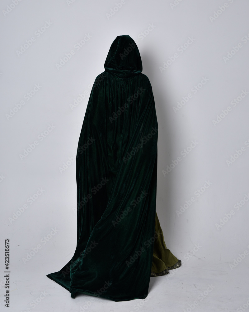 full length portrait of red haired girl wearing celtic, green medieval gown with fantasy velvet cloak. Standing pose isolated against a studio background. full length portrait of red haired girl wearing celtic, green medieval gown with fantasy velvet cloak. Standing pose isolated against a studio background.