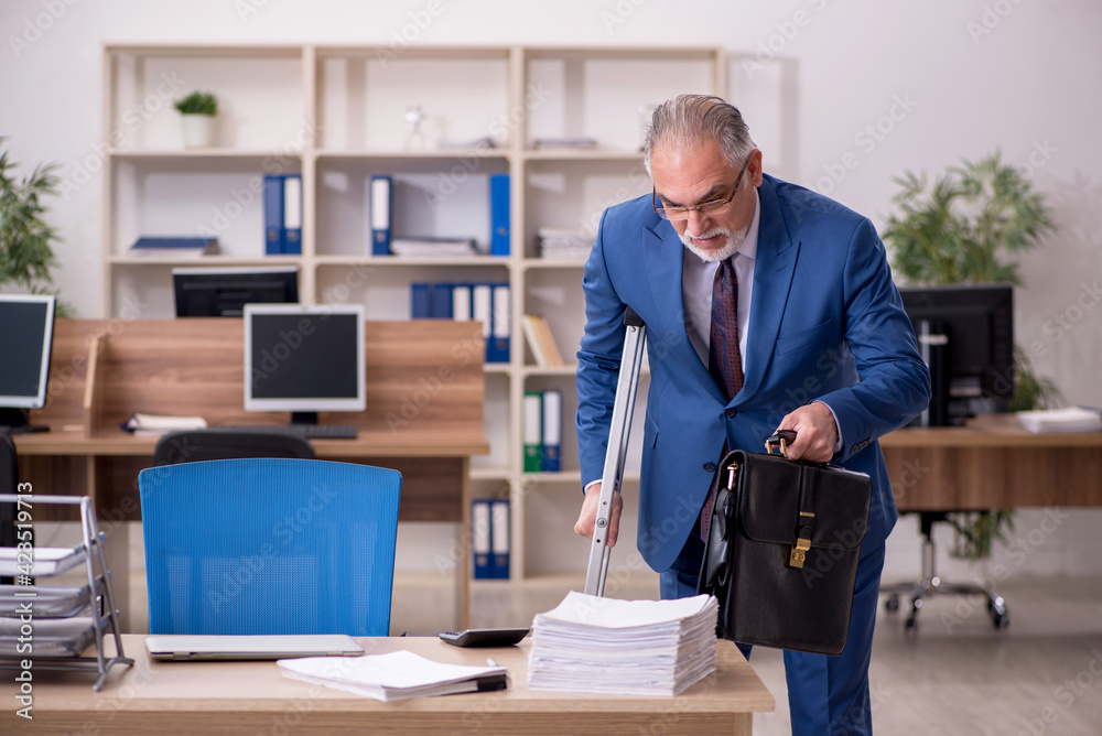 Old businessman employee after accident working in the office Old businessman employee after accident working in the office