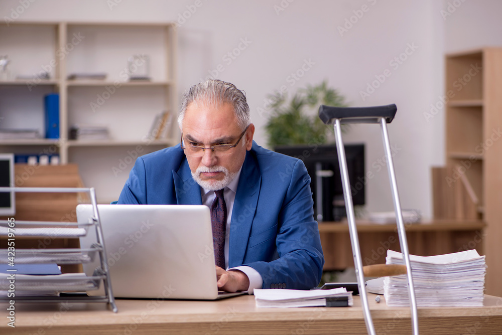 Old businessman employee after accident working in the office Old businessman employee after accident working in the office