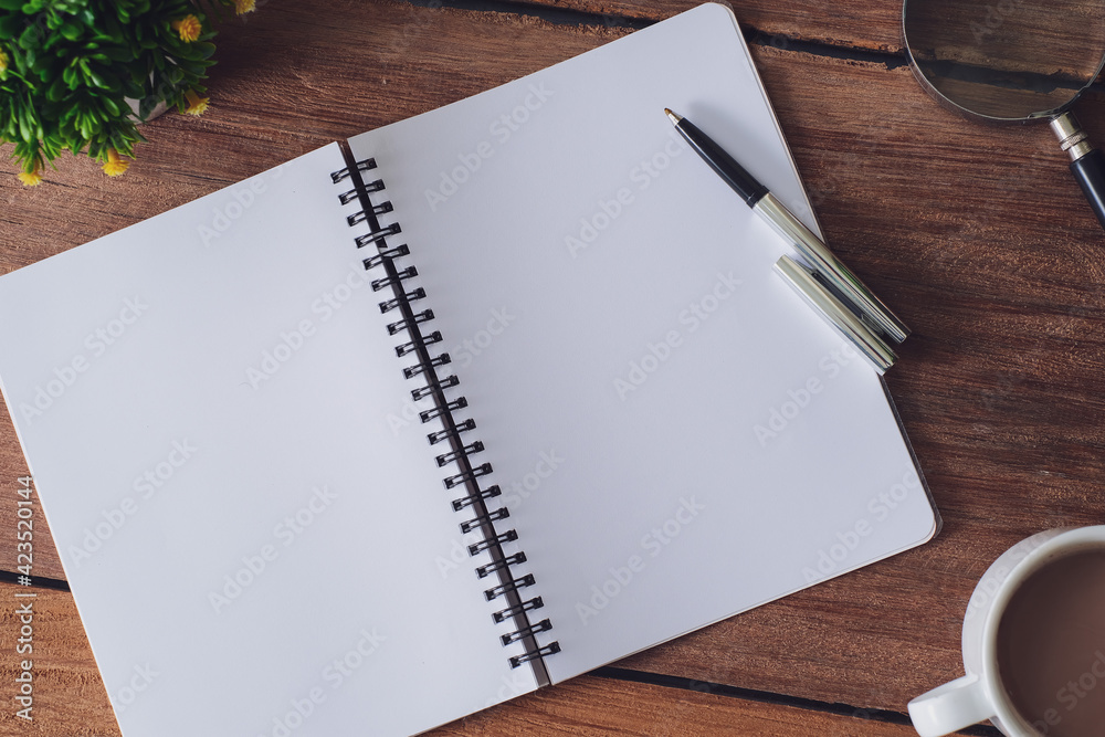 Wooden table with notebook, magnifying glass, pen, decorative plants Wooden table with notebook, magnifying glass, pen, decorative plants