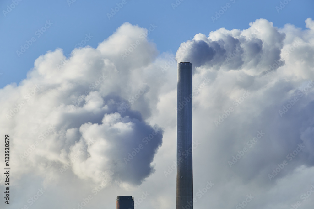 Close-up view of CHP plant pipes with smoke in the sunny day.