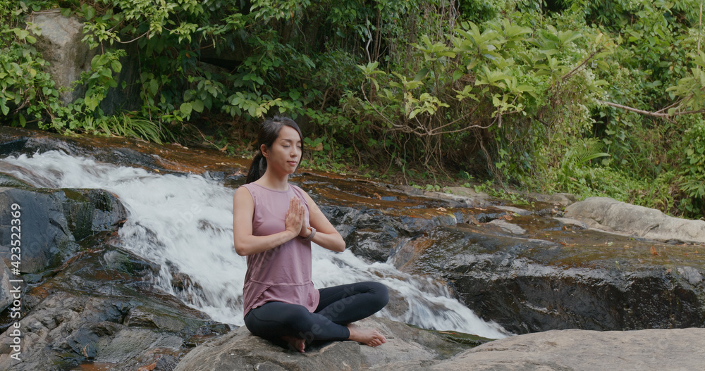 Woman do yoga with the waterfall background at waterfall